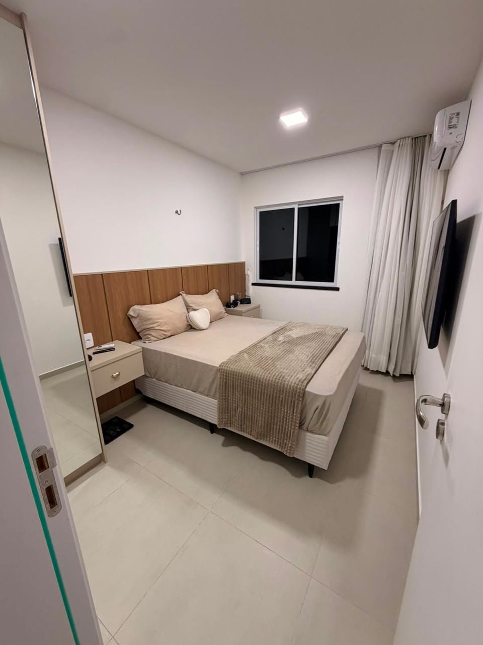 Quarto mobiliado com ar-condicionado e televisão