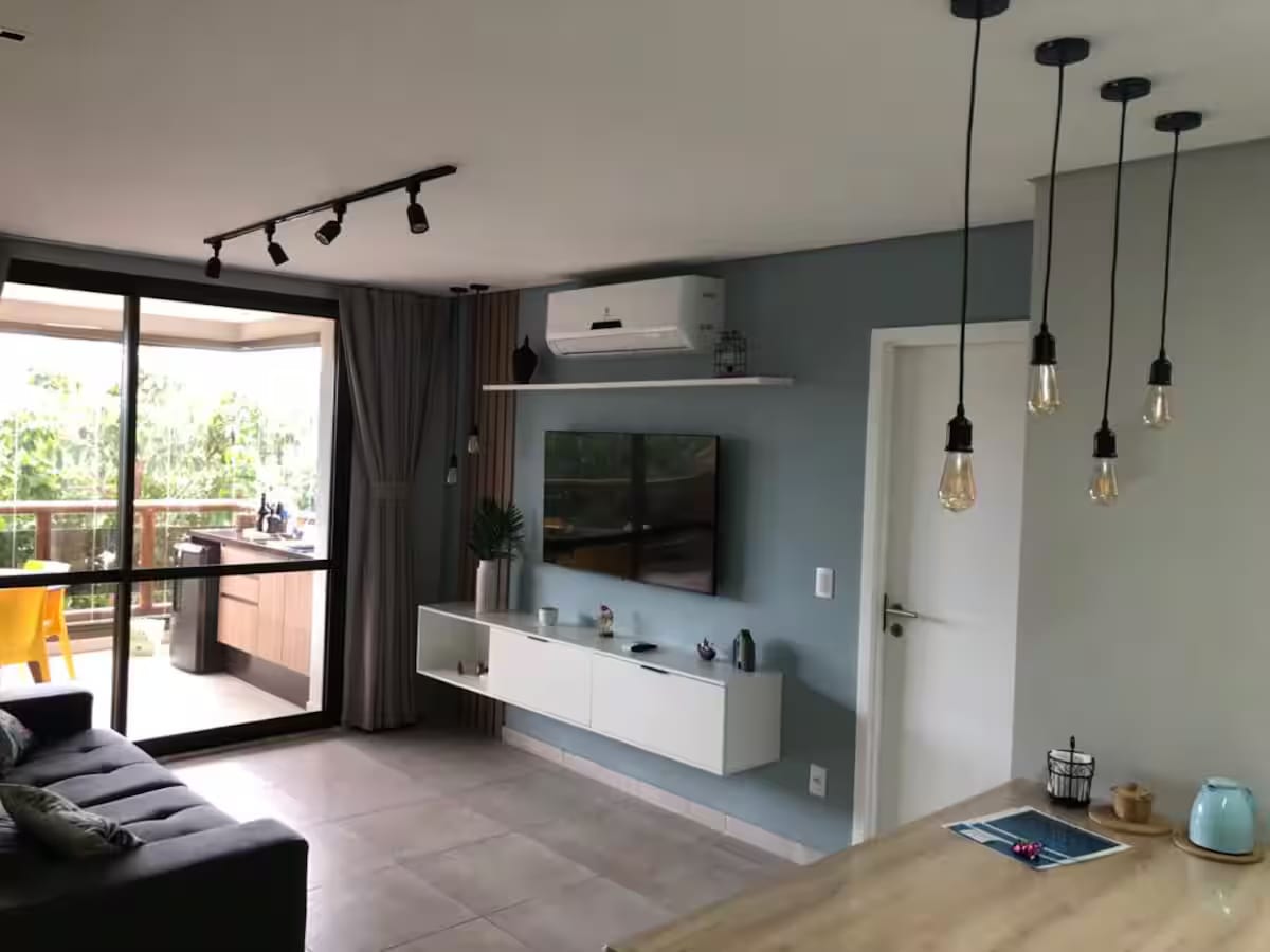 Sala com sofá, TV e acesso à varanda